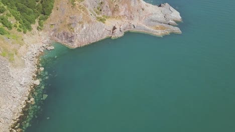 Aerial-tilt-up-towards-cliffside,-revealing-small-town