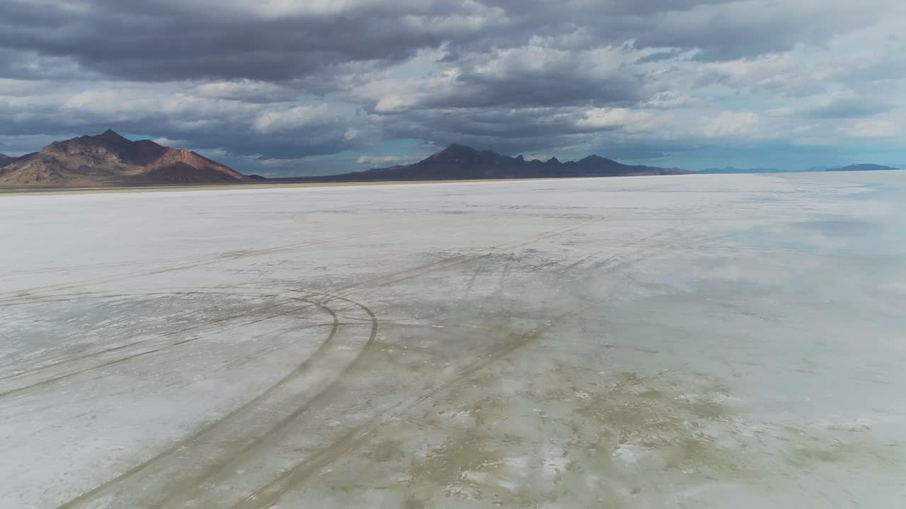 Aerial view flying over big salt flats with mountains in background