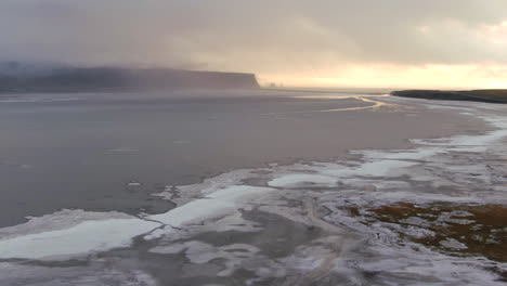 Black-Sand-Beach-panoramic-view-of-mountains,-ocean-and-birds-fluttering-around-on-an-overcast-day-in-Iceland