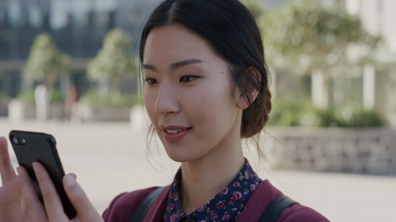 스마트폰을 사용하는 젊은 아시아 사업가 여성의 초상화 온라인 메시지 검색  ⁇ 빛 밖에서 휴대 전화로 문자 메시지를 느린 동작 여가 생활 방식