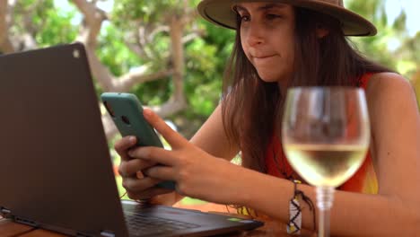 young woman working using phone, remote work concept, outdoors office sunny day with wine