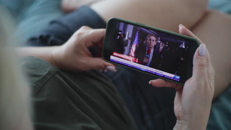 woman watching political news on smartphone