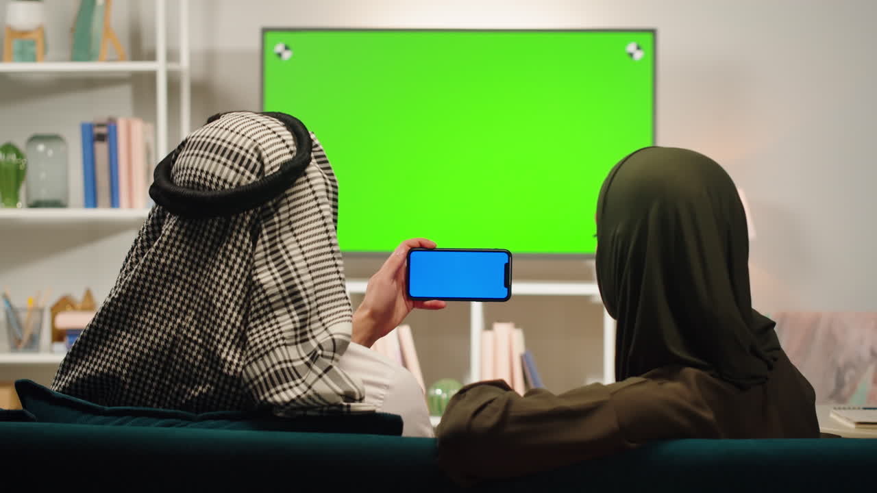 tv 를 보고 스마트폰 을 사용하는 부부