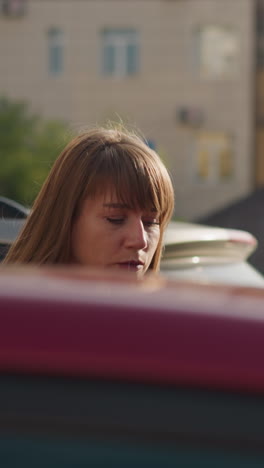 tired woman gets in red car in driver seat closing door. long-haired businesswoman gets in personal vehicle hurrying up home closeup slow motion