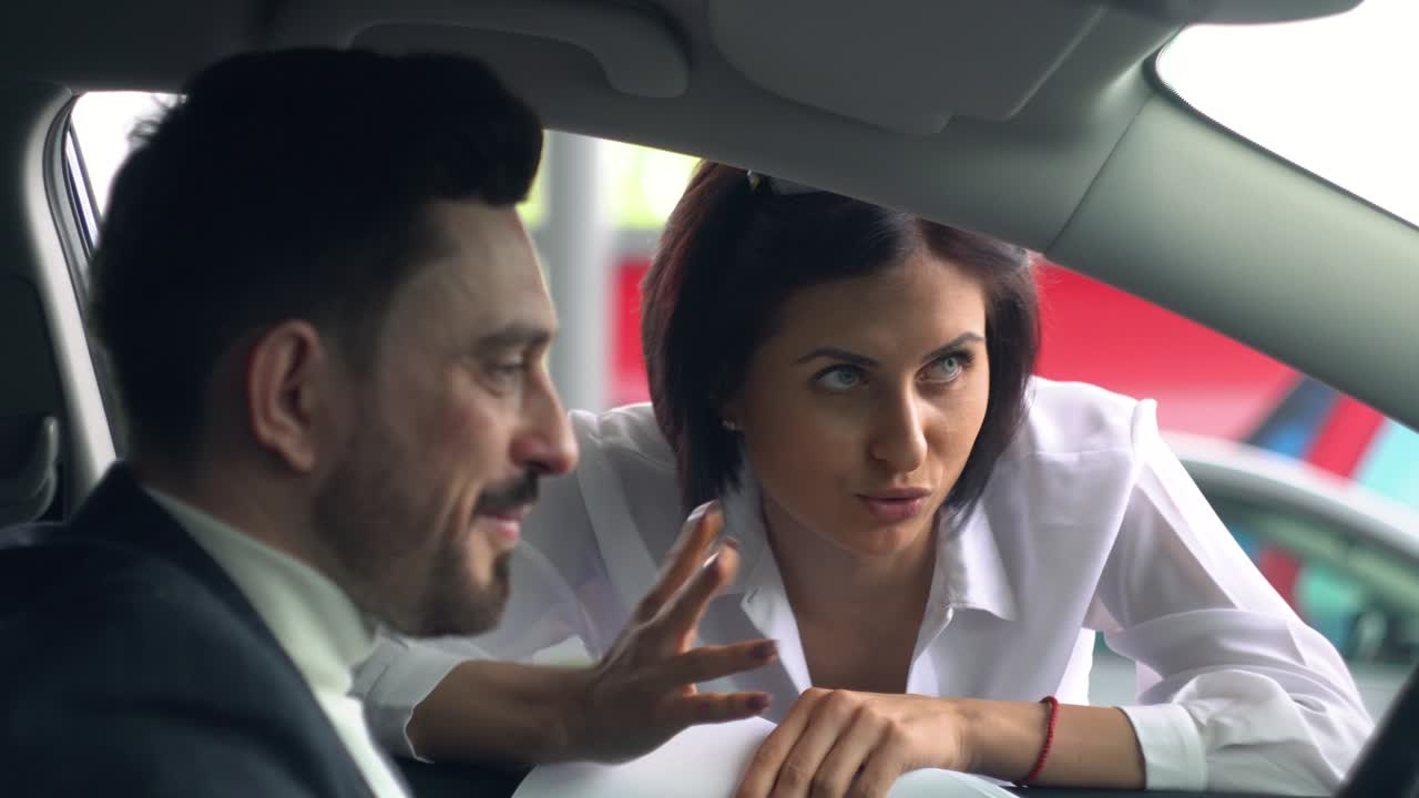 hombre exitoso sentado en el salón de automóviles y hablando con una mujer concesionaria de automóviles. negocio de automóviles, venta de automóviles