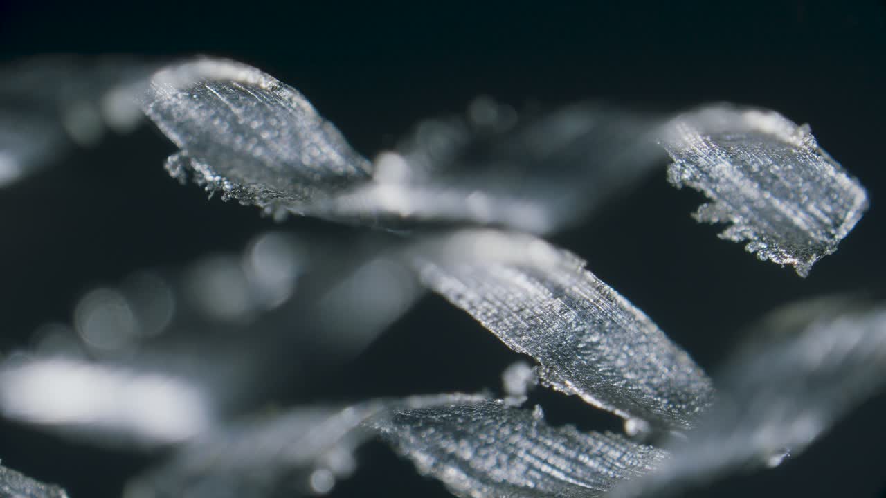Titanium metal scrap shavings in spiral form under microscope on black background