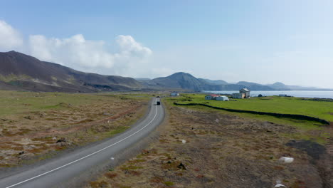 Drone-view-of-Ring-Road-the-highway-of-Iceland-that-runs-all-around-the-Island.-Aerial-view-showing-some-farmhouses-with-agricultural-machinery