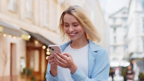 Mujer-Feliz-Usando-Un-Teléfono-Inteligente-Escribiendo-Mensajes-De-Texto-De-Aplicaciones-De-Redes-Sociales-Mensajes-De-Correo-Electrónico-En-Las-Calles-De-La-Ciudad