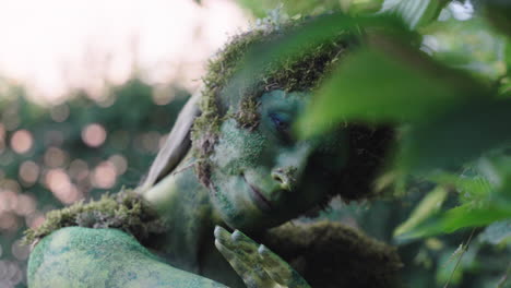 Close-up-of-a-female-model-watching-through-the-leaves-wearing-green-bodypaint,-in-the-style-of-nature-inspired-forms