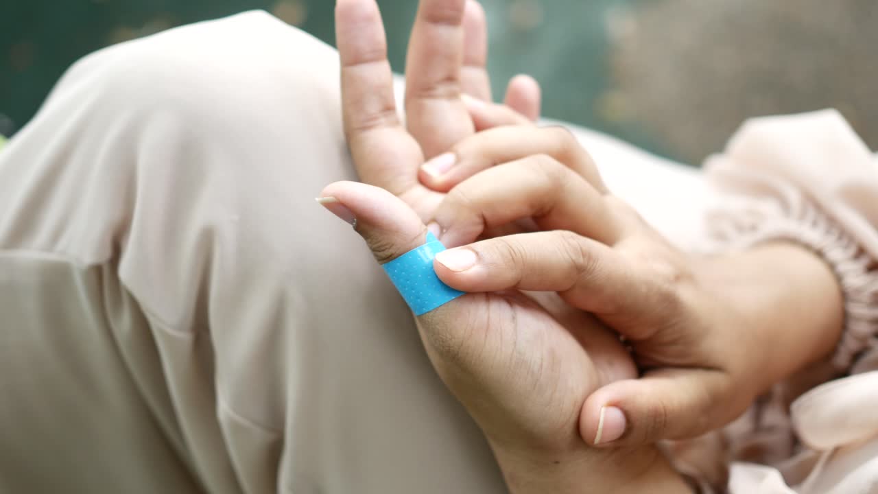 엄지손가락에 붕대를 은 여자의 손의 클로즈업