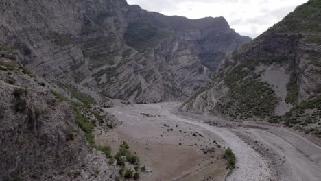 Drohnenvideo-Eines-Diagonalen-Flugzeugs,-Das-Die-Autobahn-Sh20-Zwischen-Den-Bergen-Und-Dem-Fluss-Cemi-In-Albanien-Auf-Der-Höhe-Von-Selce,-Bewölktem-Himmel-Und-Kurvenreicher-Straße-Entdeckt