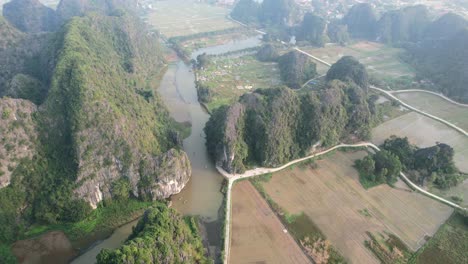 steep summits of limestone gorge revealing ngo dong river and rice fields from high above in ninh binh vietnam - aerial