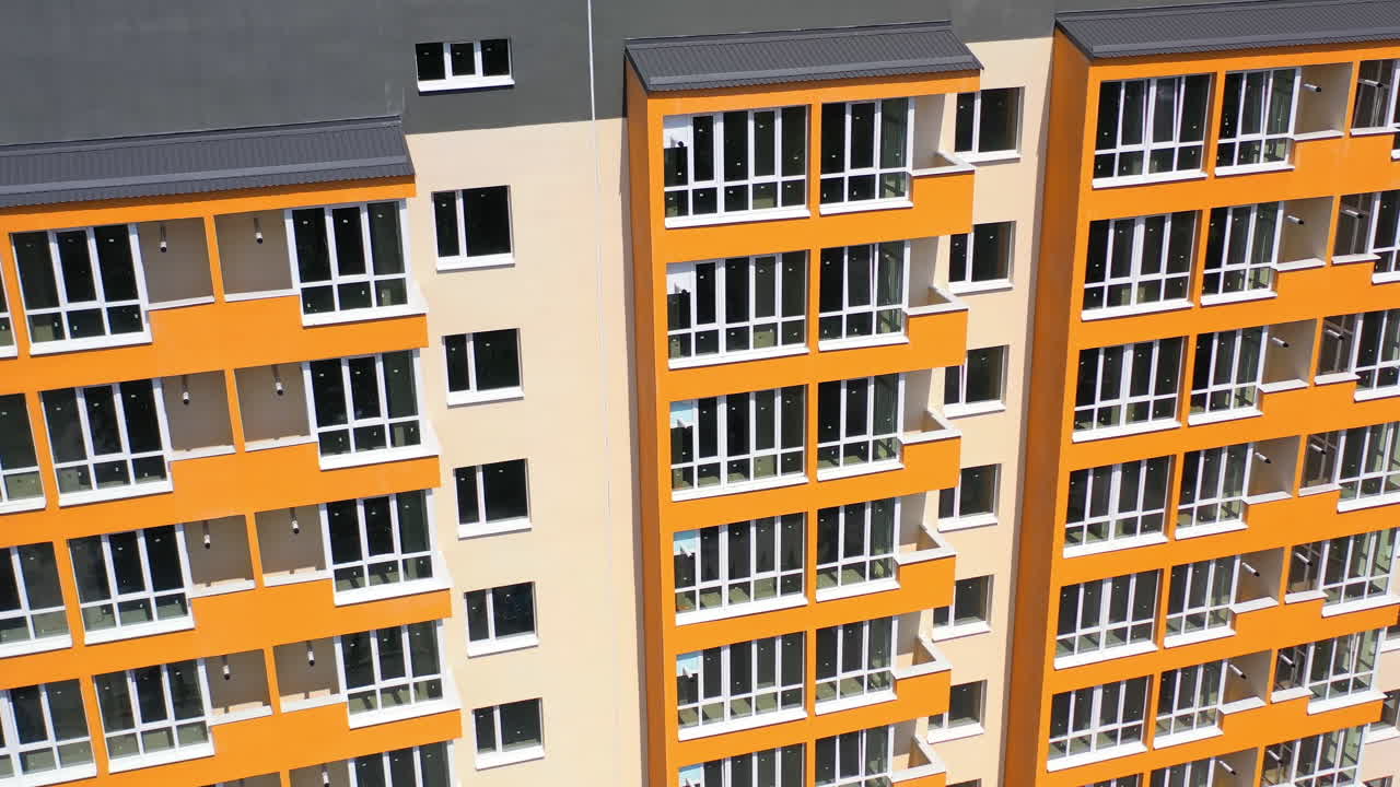 Facade of newly built skyscraper. Modern building with bright walls in the city. High raised building with large windows and balconies. Front view.