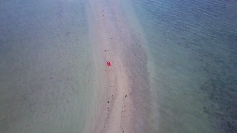 Luftaufnahme-Einer-Jungen-Brünetten-Frau-In-Rotem-Kleid,-Die-Auf-Einer-Sandbank-In-Asien-Läuft-–-Kamera-Fährt-Rückwärts-Und-Sockel-Nach-Oben