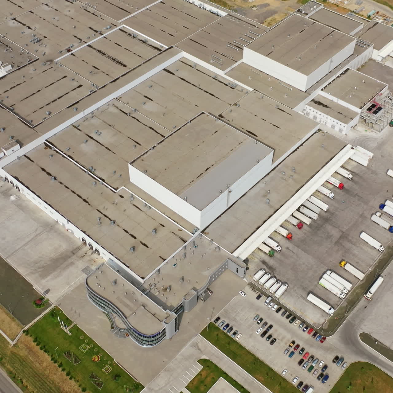 View from above on grey roof of industrial factory. Manufacturing complex with trucks parking outdoors. Aerial view.