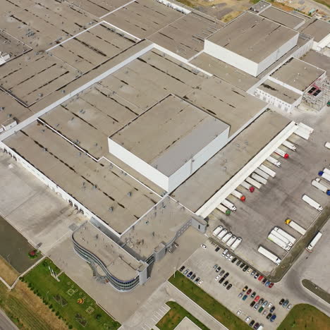 view from above on grey roof of industrial factory. manufacturing complex with trucks parking outdoors. aerial view.