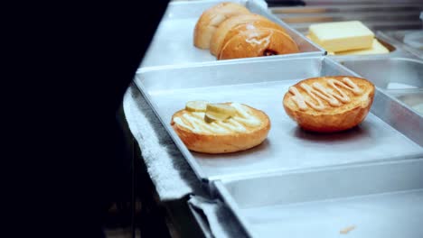 4k imágenes cinematográficas de cocina de un chef preparando y haciendo una deliciosa hamburguesa casera en la cocina de un restaurante en cámara lenta poniendo los pepinillos y las cebollas en los panes