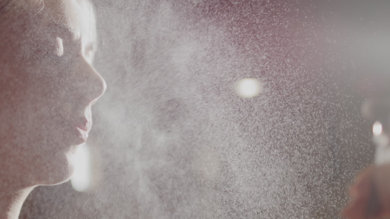 매력적인 여성은 운동 중에 냉각하기 위해 자신을 스프레이합니다.