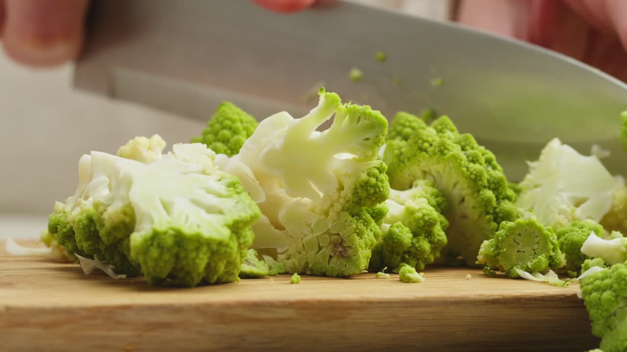 Close Up of Hands Chopping Fresh Romanesco Broccoli on a Cutting Board