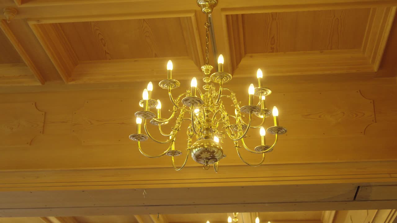 Elegant chandelier hanging from wooden ceiling – warm interior detail shot