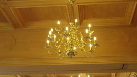 elegant chandelier hanging from wooden ceiling – warm interior detail shot