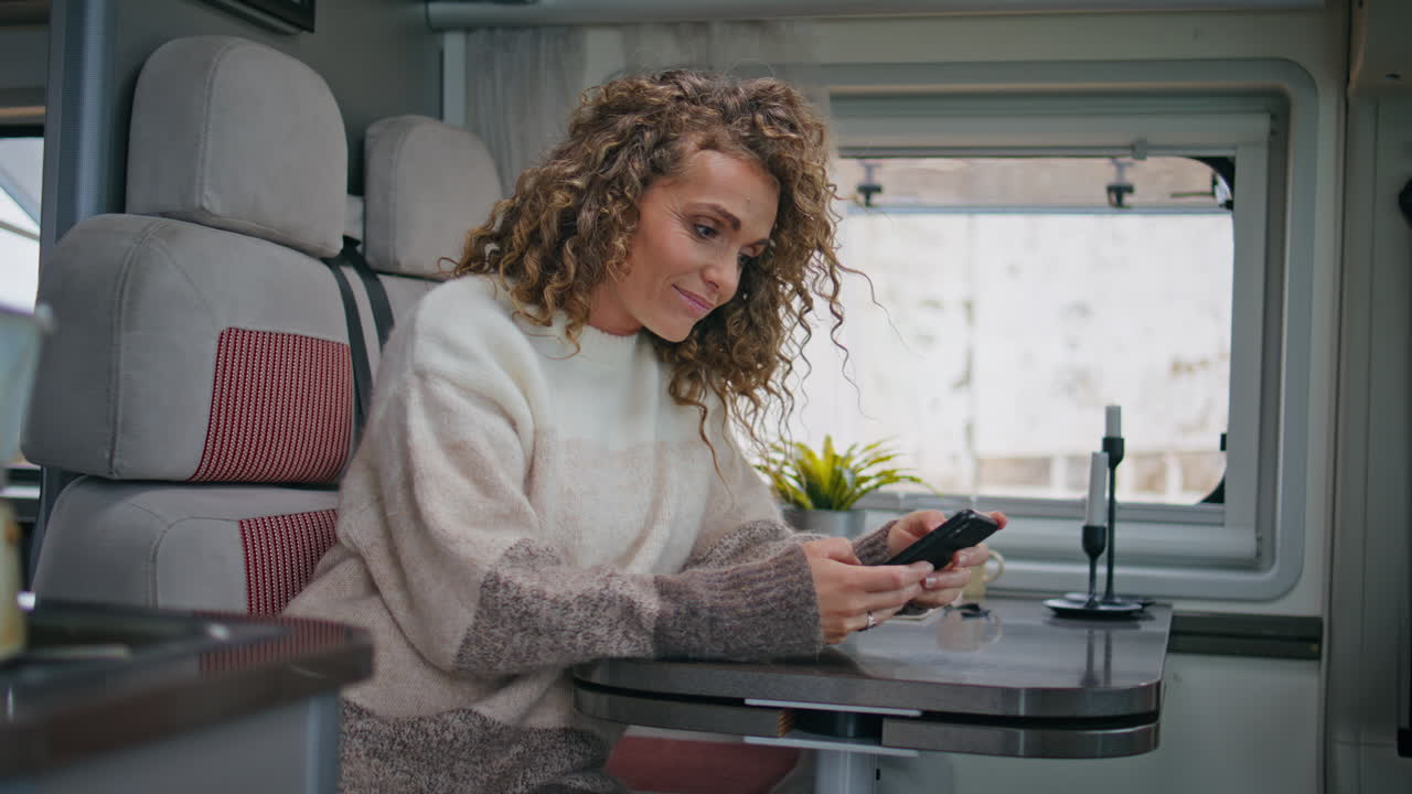 feliz trabajador independiente leyendo sms teléfono inteligente sentado en la mesa remolque de cerca.