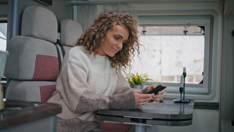 happy freelancer reading sms smartphone sitting table trailer close up.