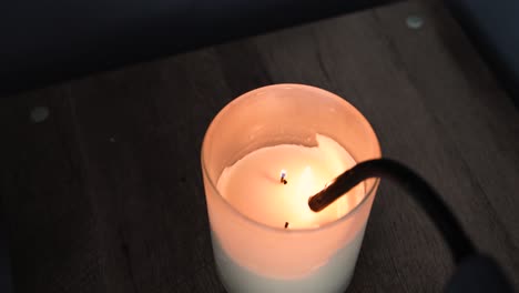 Lighting-a-white-pineapple-candle-with-a-gooseneck-lighter-in-the-dark-with-a-wooden-backdrop