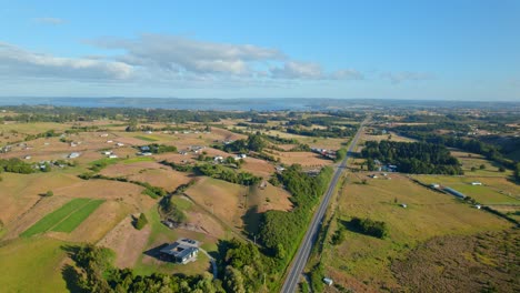 Luftaufnahme-Einer-Straße-Inmitten-Der-Ackerflächen-Des-Sonnigen-Chiloé,-Chile