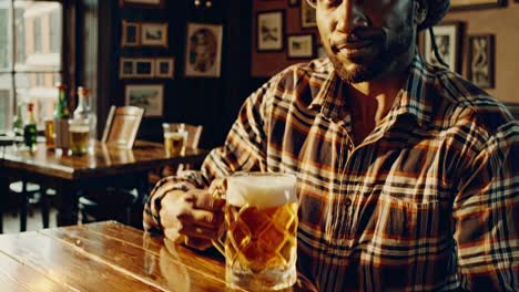 man holding a glass of beer in a cozy pub, savoring a refreshing moment while surrounded by a warm and inviting atmosphere perfect for socializing with friends