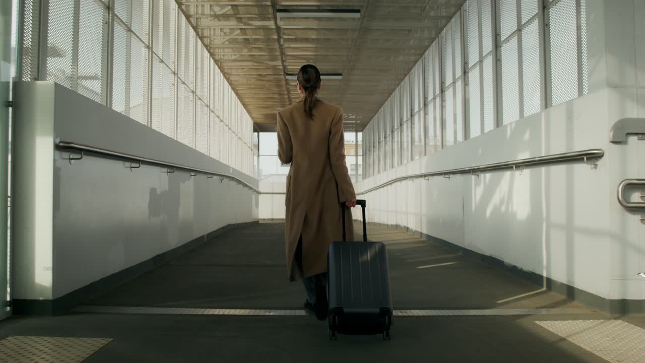 Mujer caminando por la pasarela del aeropuerto con equipaje