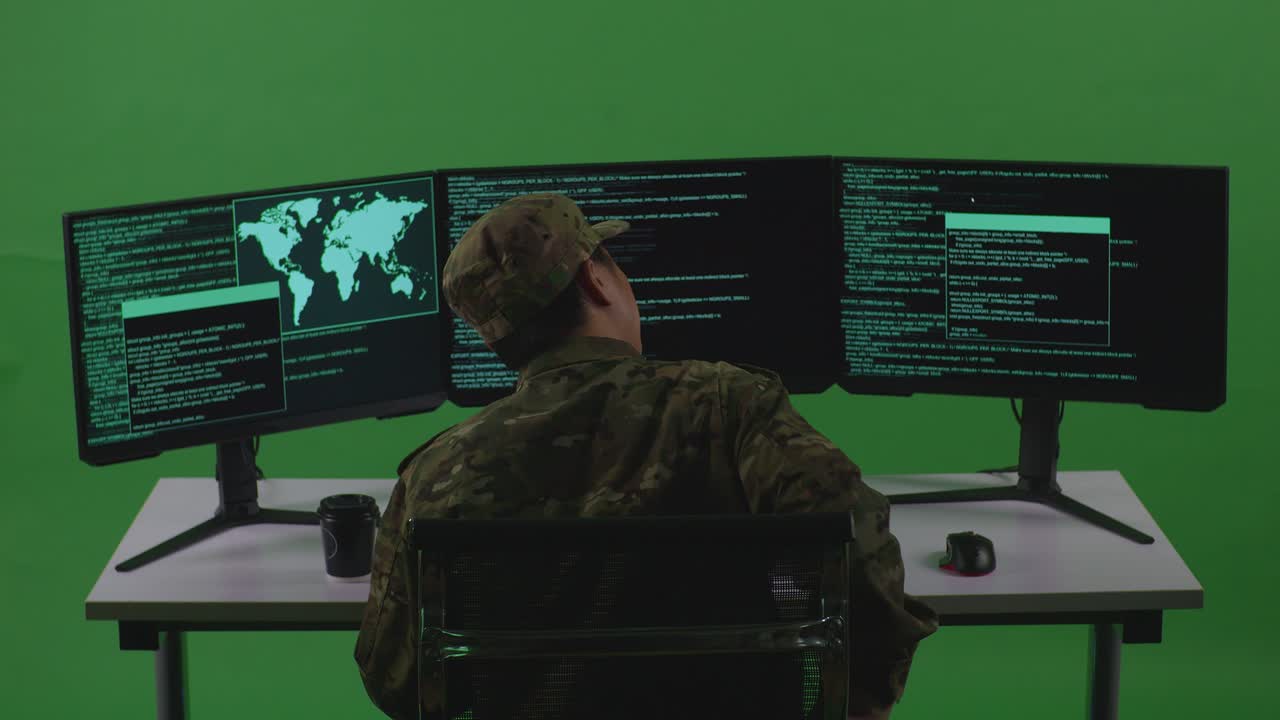 Back View Of Asian Man Soldier Developer Having Backache While Write Code With Multiple Computer Screens In Green Screen Studio