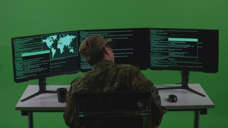back view of asian man soldier developer having backache while write code with multiple computer screens in green screen studio