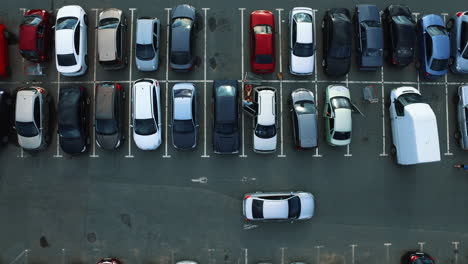 aerial view car moving at mall parking lot. copter flying above mall parking