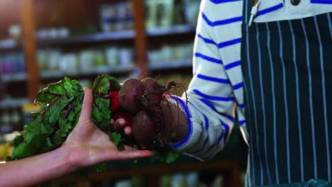 Staff-assisting-woman-in-selecting-fresh-beetroots