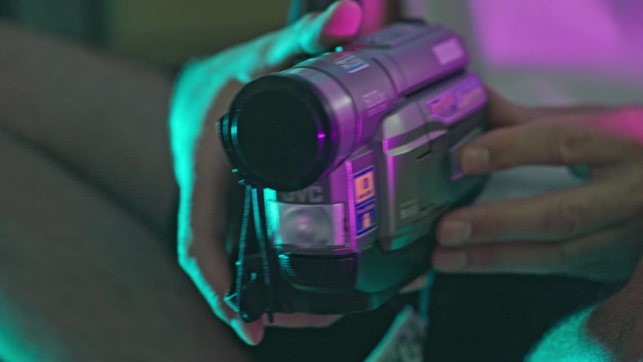 Hands Operating a Vintage JVC VHS Camcorder with Neon Lighting