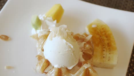 using fork to eat croffle waffles on plate with ice-cream and caramel banana