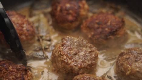 closeup of anonymous person turning cutlets in sauce