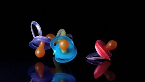 four baby pacifiers falling