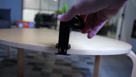 close-up shot of hands installing a clamp mount on a wooden table. ideal for tech, diy, tutorials, or product assembly themes.