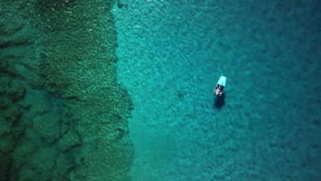 Vista-Aérea-Ascendente-De-Un-Barco-Flotando-Sobre-Un-Arrecife-De-Coral-Sobre-Aguas-Cristalinas