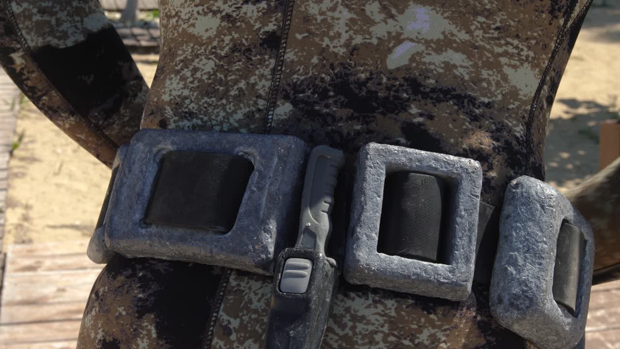 웨이트 벨트를 매는 스쿠버 다이버의 클로즈업