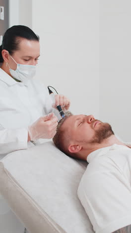 tricólogo haciendo hombre mejorar el crecimiento del cabello procedimiento dermapen microneedling inyecciones de vitaminas