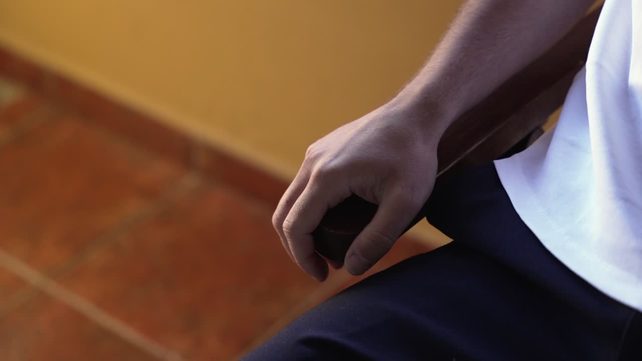 close up de una persona sentada, la mano descansando en una silla, creando un estado de ánimo contemplativo