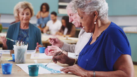 group of retired seniors attending art class in community centre with teacher