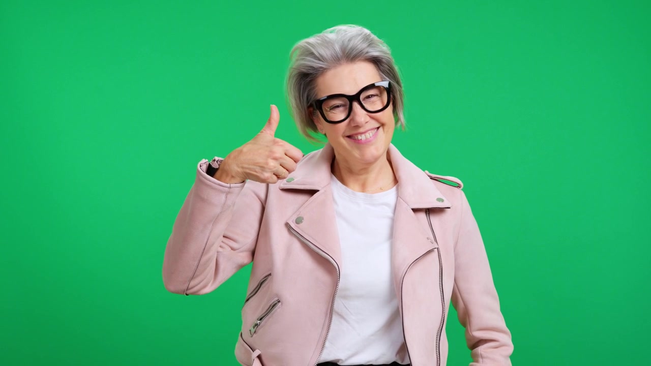 Donna matura elegante che fa il pollice in su su sfondo verde