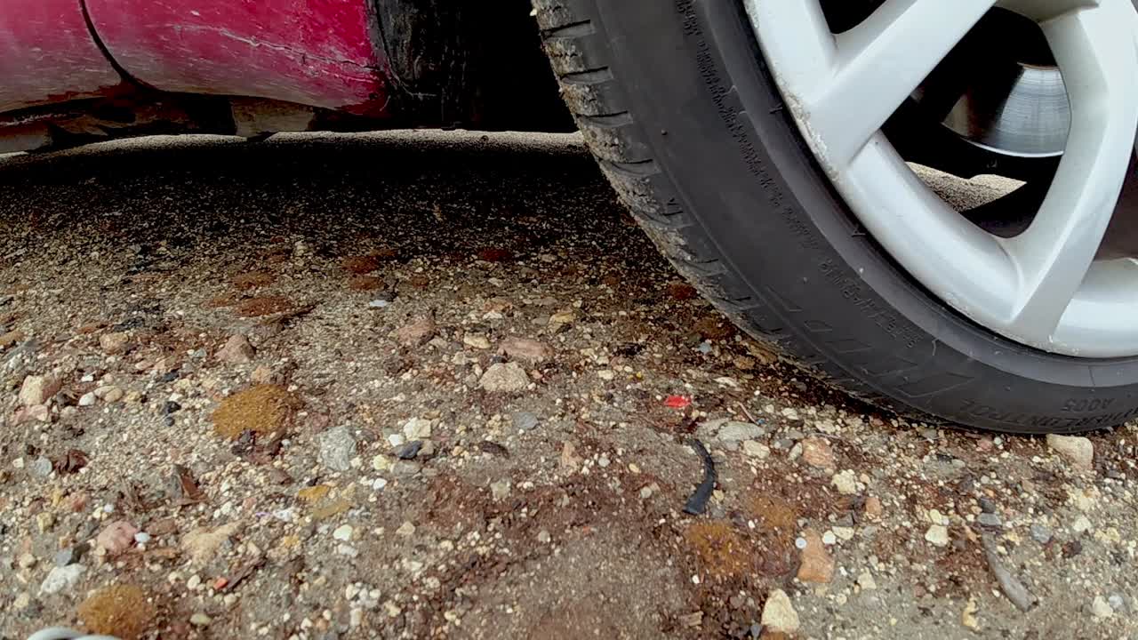 Focused car wheel accelerating in slow motion on sandy ground