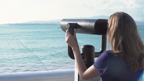 woman looking through binoculars at the ocean