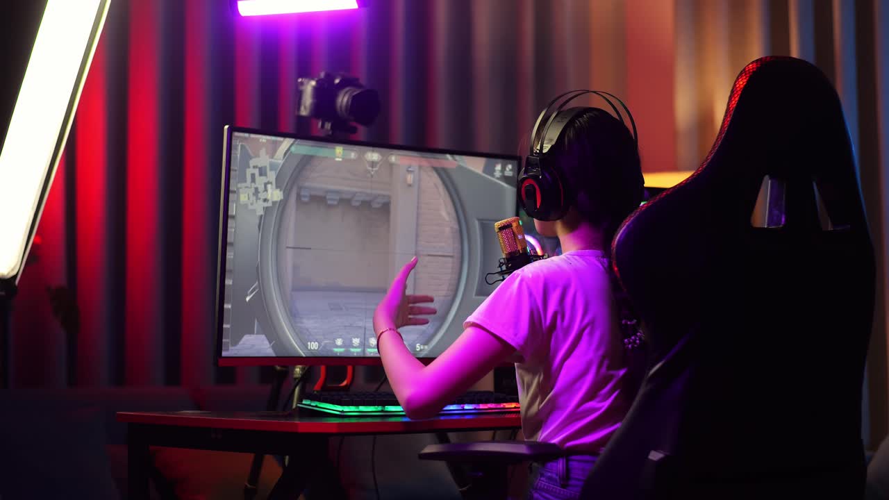 Back View Of Asian Girl Streamer Playing Game Over Network On Personal Computer. Challenge And Bully Competitor, Live Stream Video Game, Desk Illuminated By Rgb Led Strip Light