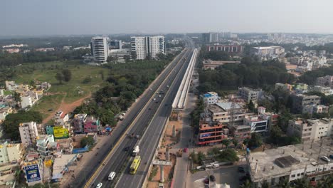 aerial video of a rapidly growing indian highway featuring a service road, fast-moving cars, and residential and commercial structures